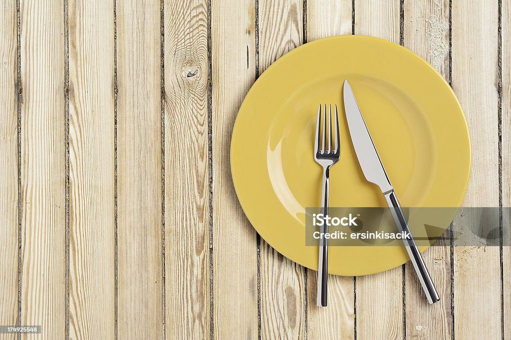 Piatto con coltello, cucchiaio e forchetta sul tavolo di legno - Foto stock royalty-free di Argentato