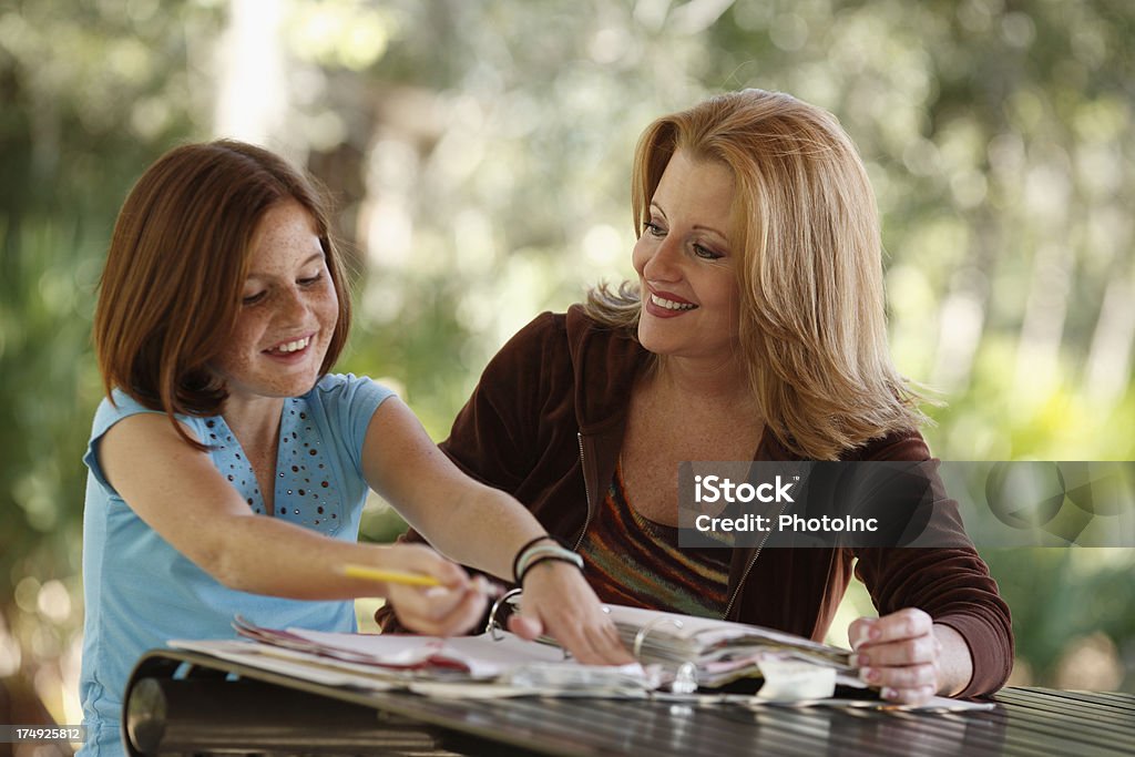Madre e hija haciendo los deberes sonriendo mientras - Foto de stock de 10-11 años libre de derechos