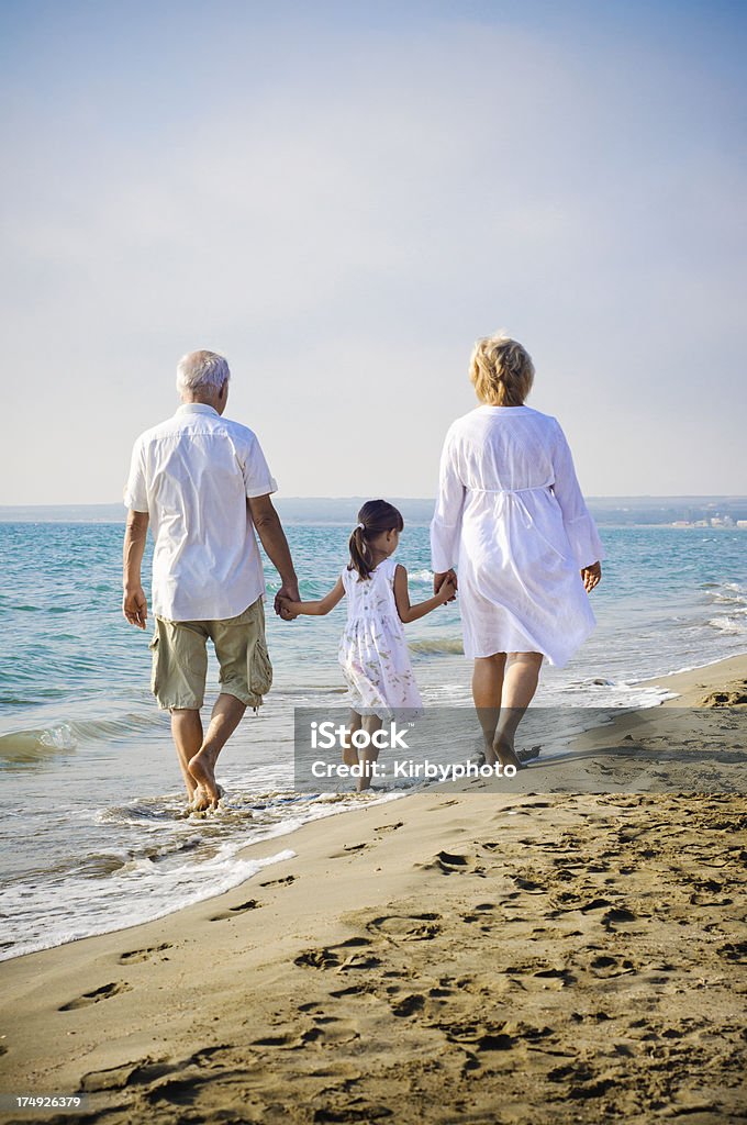Niña y su abuelos Caminatas en la playa - Foto de stock de Niño libre de derechos