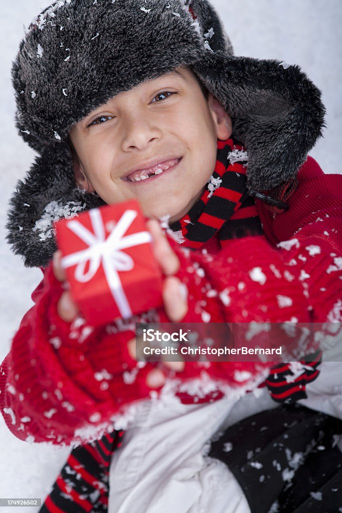 Jeune garçon assis dans la neige avec cadeau de Noël - Photo de 8-9 ans libre de droits