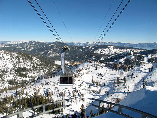 A ski lift ascends a snowcovered mountain with a picturesque landscape of trees, slopes, and freezing temperatures in a natural winter terrain