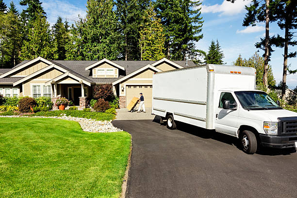 Delivery Man with Truck Photo of a delivery man moving cardboad boxes from truck to house with hand truck. moving van stock pictures, royalty-free photos & images