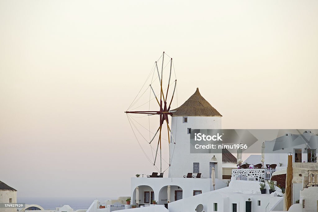 Molino de viento en sunrise en Oia Village. Santorini. Grecia. - Foto de stock de Acantilado libre de derechos