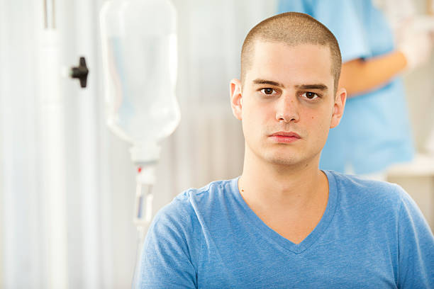 young man receiving chemotherapy at home - kaal geschoren hoofd stockfoto's en -beelden