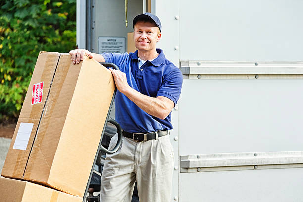Delivery Man Photo of a delivery man with cardboard boxes on hand truck. mover delivery person box hand truck stock pictures, royalty-free photos & images
