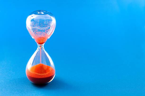 Red hourglass on blue background Hourglass on blu background half past stock pictures, royalty-free photos & images