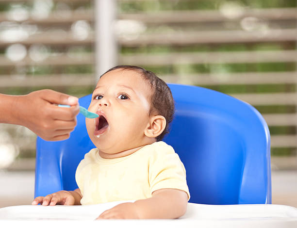 Eating baby. Very cute mixed race baby eating, sitting in his diner chair. baby spoon stock pictures, royalty-free photos & images