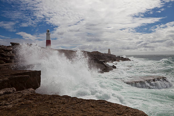 Portland Bill Lighthouse "Portland Bill Lighthouse viewed from Pulpit rock, waves crashing onto coast." bill of portland stock pictures, royalty-free photos & images