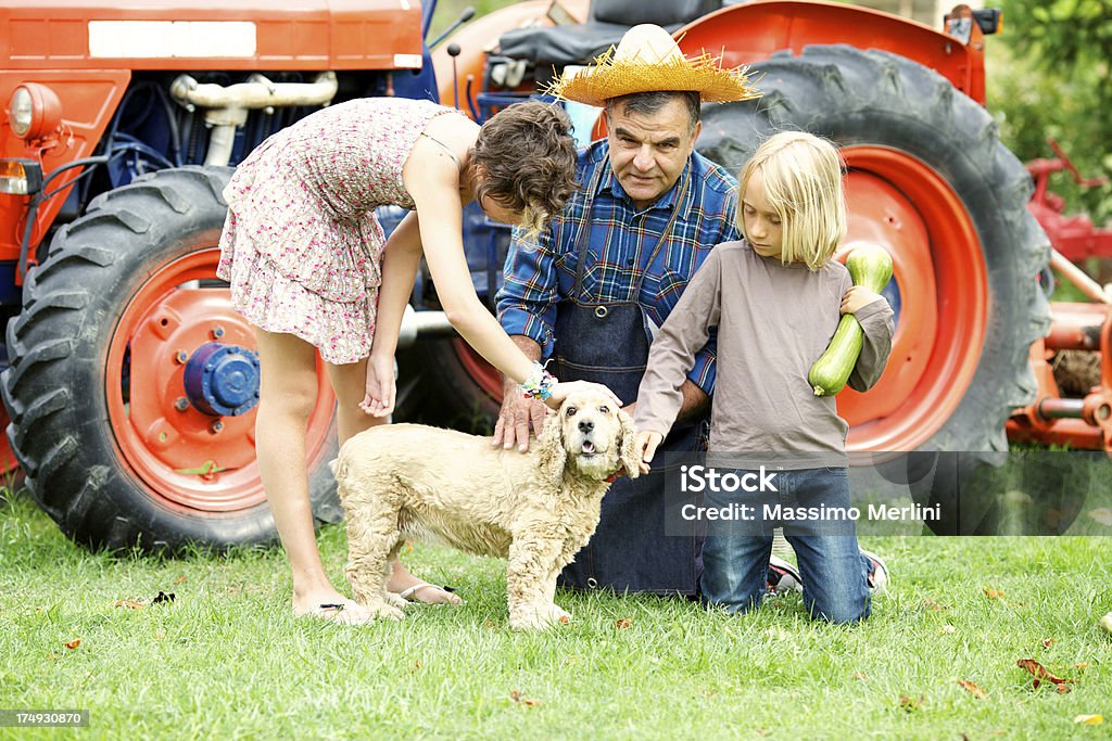 Nonno con nipoti accarezzano loro cane - Foto stock royalty-free di Agricoltore