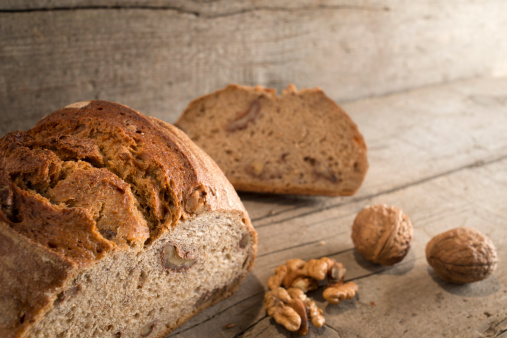 View at a walnut bread  on a wooden background. Selective focus on the loaf in the foreground.