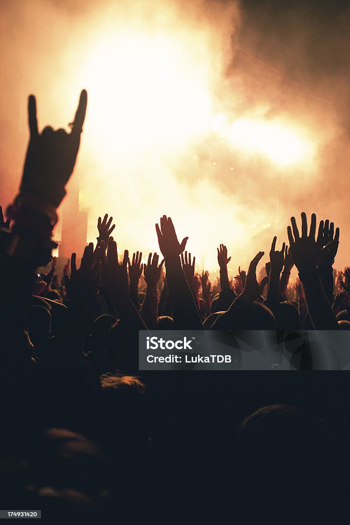 Concert crowd silhouettes of people on a rock concert raising hands, stage light in background.   Alternative Rock Stock Photo