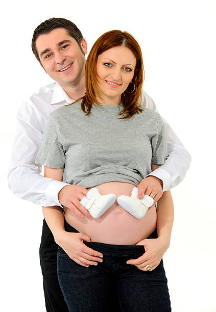 Beautiful young couple expecting baby on white background