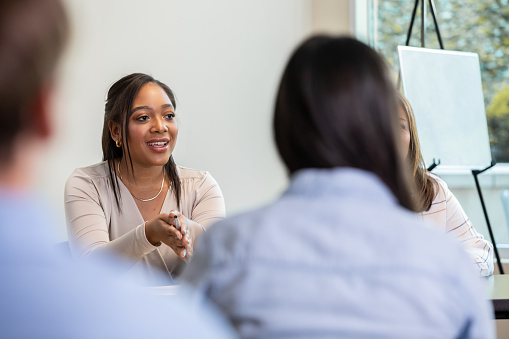 In a meeting with a panel of spectators, a young woman assumes the role of the leader