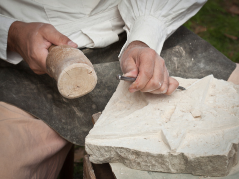 Hands carving a star out of white stone.See also: