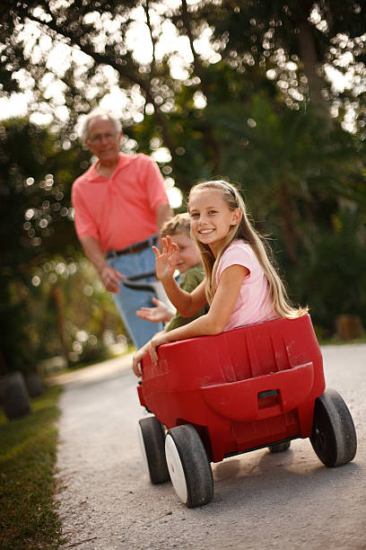 istock Grandfather pulling grand kids in red wagon 174933746