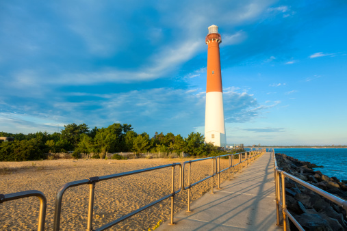 The Barnegat Lighthouse, also known as Old Barney, is located at Barnegat Light, New Jersey. A railing guides the way along a concrete walkway to the 40-foot-tall red and white lighthouse which is accessible to tourists willing to climb its 217 steps. 