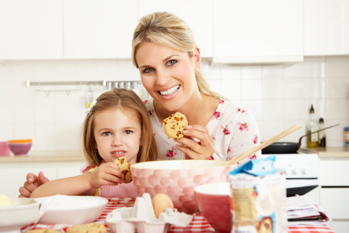 Mother And Daughter Baking In Kitchen Smiling To Camera.