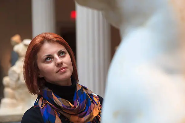 Woman in museum looking at fine art statue.