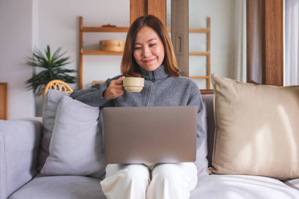 istock Portrait image of a young woman drinking coffee while working on laptop computer at home 1749347635