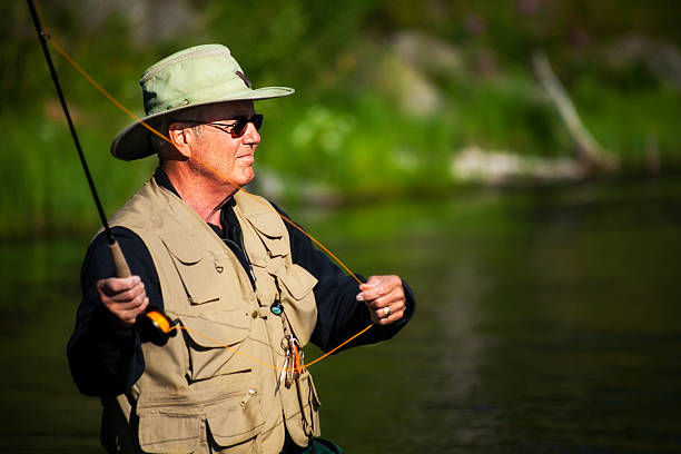 Mature Male Fly Fisherman Preapares to Cast with Fly Rod stock photo
