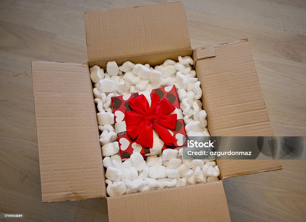 Gift in box of packing foam "Christmas present in packing peanuts inside of a cardboard shipping box, high angle view" Cardboard Box Stock Photo