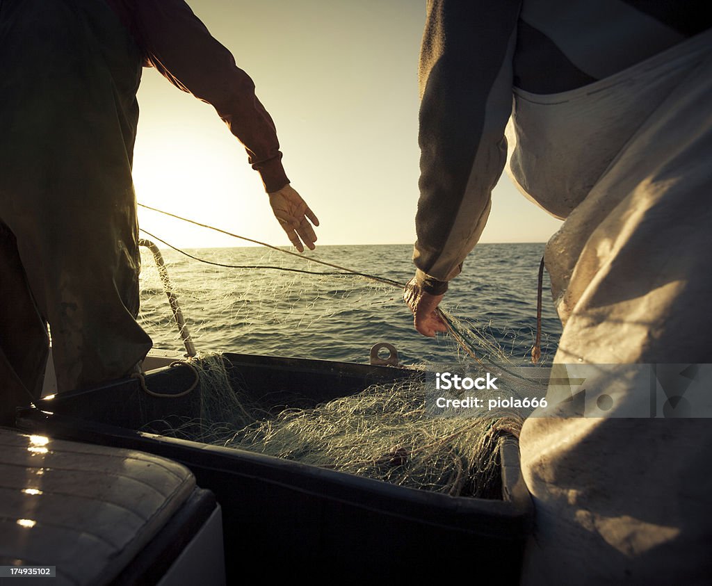 Fishermen at work, pulling the nets "Fishermen boats in action, Italy.Pulling up the nets from the sea.More Trawler Fishing Videoclip" Fisherman Stock Photo