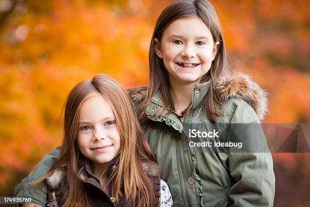 Due Piccole Sorelle In Piedi Fuori In Fresca Giornata Autunnale - Fotografie stock e altre immagini di Abbracciare una persona