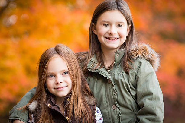 duas irmãs mais jovens em pé do lado de fora, em dia frio, outono - little girls autumn child red hair - fotografias e filmes do acervo