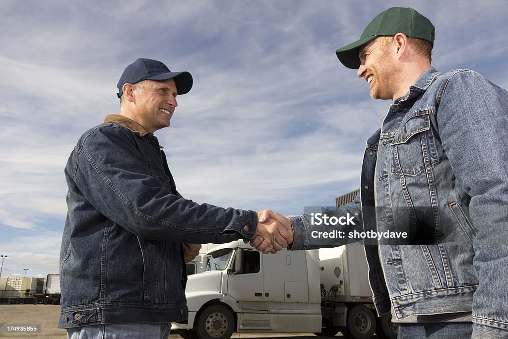 Truck Driver Handshake A royalty free image from the trucking industry of two truck drivers shaking hands in front of a truck. Truck Stock Photo