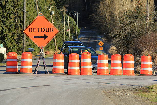 Road Closed A horizontal image of a road barricaded with traffic control barrels and a detour sign. traffic cone photos stock pictures, royalty-free photos & images