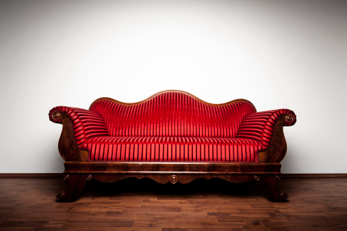 Photography of a restored original Biedermeier sofa (1815-1848). Wide angle view. Dramatic lighting (vignette not added artificially).