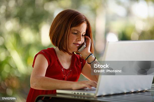 Giovane Ragazza Parlando Sul Cellulare Mentre Utilizzando Il Computer Portatile - Fotografie stock e altre immagini di 8-9 anni