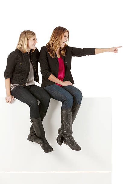 istock Females sitting on the ledge of a wall and pointing 174937247