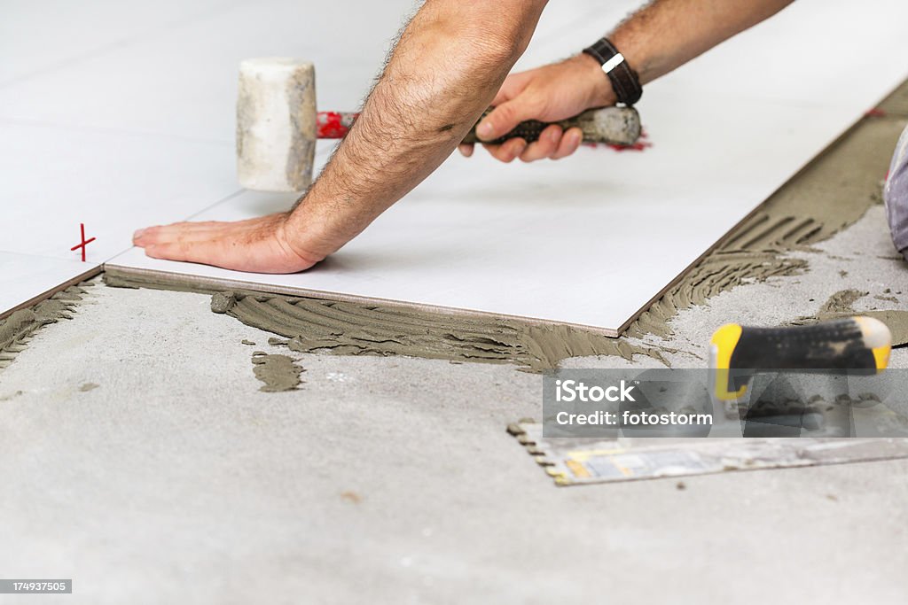 Home improvement - Worker installing tiles Adult Stock Photo