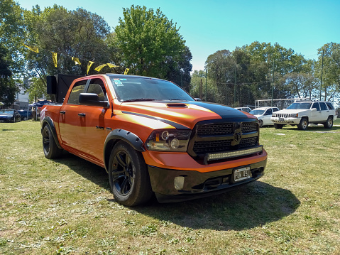 Remedios de Escalada, Argentina - Oct 8, 2023: Modern orange Dodge RAM Hemi quad cab pickup truck on the lawn at a classic car show in a park. Sunny day