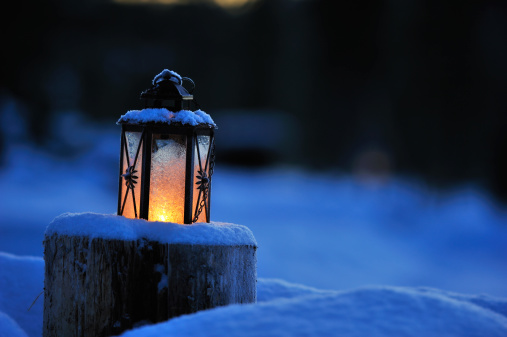 Christmas lantern lit by candlelight at dusk.