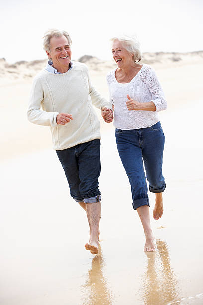 istock Senior Couple Running Along Beach Together 174937870