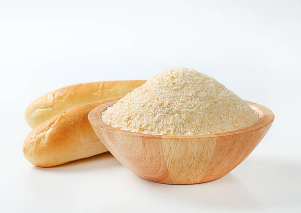 wooden ceramic bowl of fresh breadcrumbs and hard rolls on a white background
