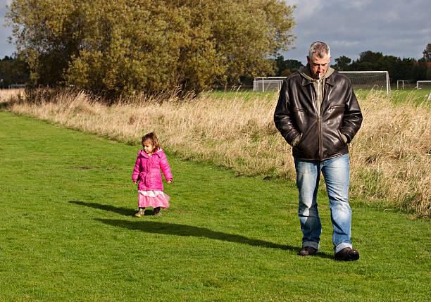 abuelo caminando en el parque con granddaughter - coat grandfather grandchild granddaughter fotografías e imágenes de stock