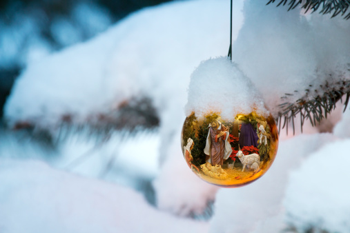 This Christmas Tree Ornament brightly reflects a Nativity Scene with the newborn baby Jesus on a snow Christmas morning outdoors.