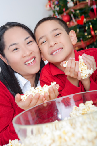 Happy asian mother and son stringing popcorn