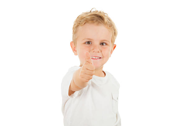 Thumbs up! Smiling happy cute boy, studio shot, focus on thumb, isolated on white