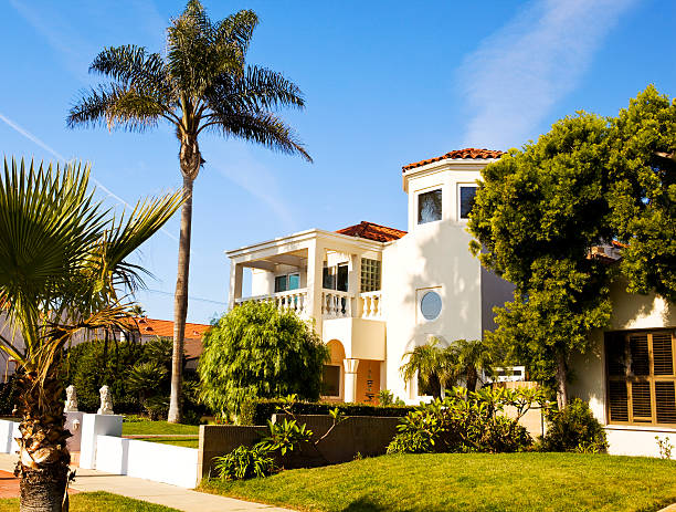 Venice, FL, USA - March 21, 2016: Luxury Elegant New Beach Home with Blue exterior in Venice, Florida, USA. Landscaped front yard , green grass and bushes is in foreground. Trees and blue sky with clouds are in background.