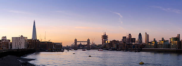 Tower Bridge and the City of London skyline sunset panorama "Panoramic view across London of the Thames, Tower Bridge and the financial skyscrapers of The City at dusk. The panorama shows several periods of development in London's history; Victorian, 80's docklands redevelopment and more recently the financial skyscrapers in The City. The Shard, the tallest skyscraper in London was completed in 2012, a new skyscraper nicknamed the Walkie-Talkie is under construction to the right of Tower Bridge." panoramic riverbank architecture construction site stock pictures, royalty-free photos & images