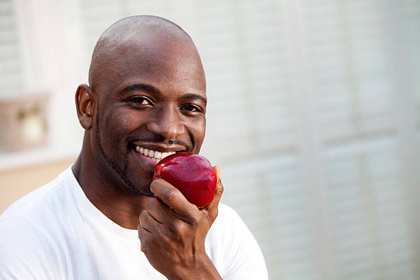 istock Young man with great teeth eating a juicy red apple 174940801