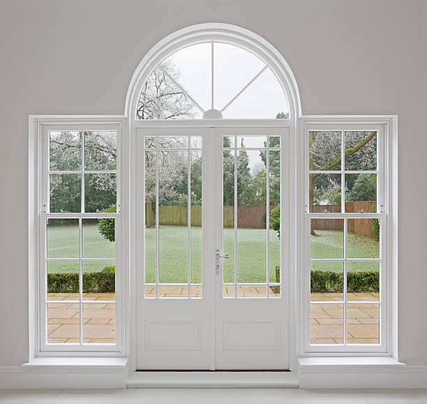 beautiful white patio doors a beautifully crafted set of patio doors in a large mansion house with views through to a frosty garden and patio during early morning. The frames are constructed from wood to the highest of standards. The style is Georgian but the doors in the centre have an almost Art Deco feel to them. The frame is set in a light grey wall. window latch stock pictures, royalty-free photos & images