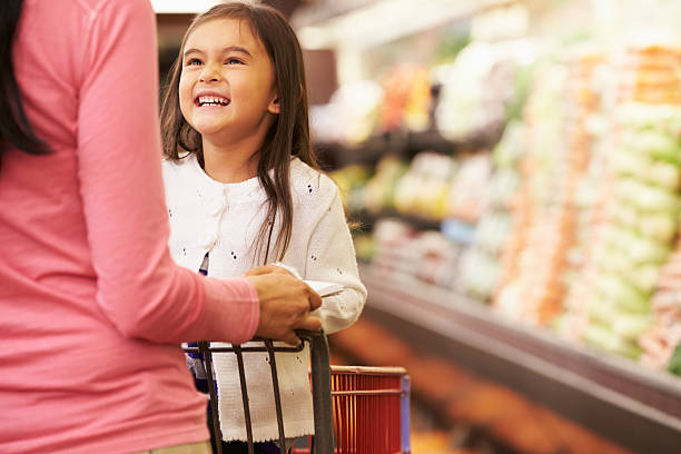 Close Up Of Mother Pushing Daughter In Supermarket Trolley Close Up Of Mother Pushing Daughter In Supermarket Trolley Smiling supermarket family retail cable car stock pictures, royalty-free photos & images