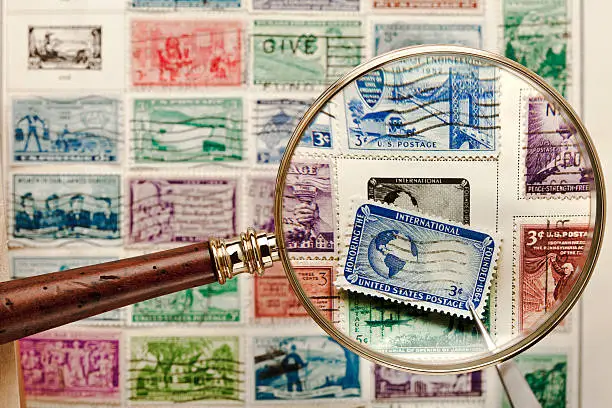 This images was rejected before for containing the American Red Cross logo, the name and logo have been removed from this image.  Old, cancelled stamps shown with Magnifying Glass & Tweezers used for the hobby of stamp collecting - a lot of great color and detail. The slight distortion on the edges of the stamp is from the distortion of the magnifying glass, the center of the Stamp is sharp.     http://i658.photobucket.com/albums/uu308/davidjames08/PostCards_Stamps-GreenTop.jpg