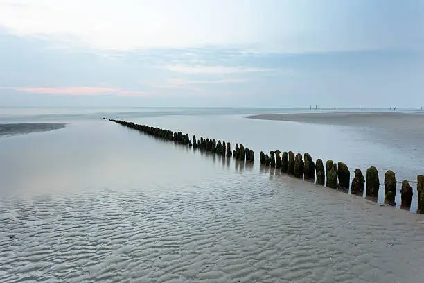 "A row of poles leading into the North Sea in Norderney, Germany. Long exposure shot."