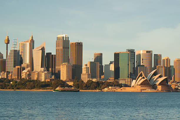 Sydney's skyline is bathed in a golden sheen as the sun rises opposite.